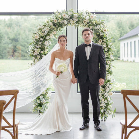 bride and groom in front of wedding arch